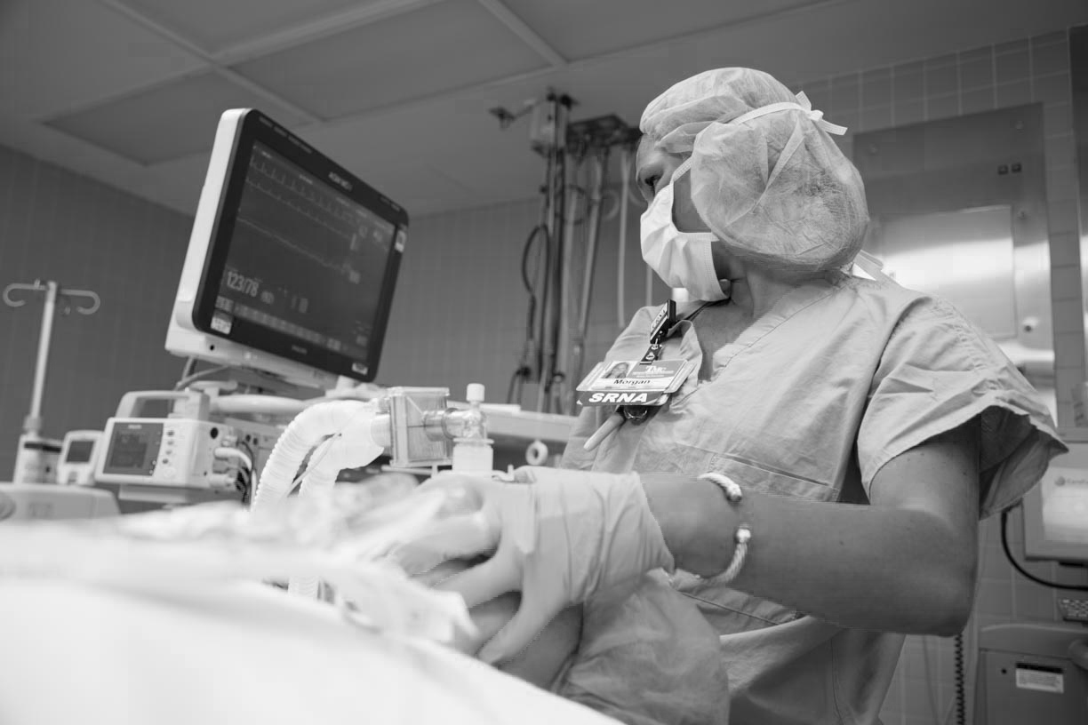 crna watching monitor while applying anesthesia to patient